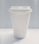 Blank white paper coffee cup isolated on a gray background. Unbranded single-use cup