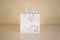 Blank white paper gift bag mock up standing on a wooden table. E