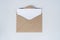 Blank white paper is placed on the open brown paper envelope. Mock-up of horizontal blank greeting card. Top view of Craft paper