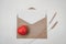 Blank white paper is placed on open brown paper envelope with red heart with Bristly foxtail dry flower on white background.