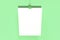 Blank white poster with binder clip mockup on green background