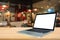 Blank white screen laptop computer on wood table top with cafe restaurant abstract bokeh light blur background