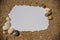 Blank white sheet of paper on white sand with seashells and stones. Message by the sea, romance, valentine's