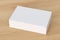 Blank white wide flat box with closed hinged flap lid on wooden background.