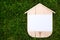 Blank Wood House with blank paper on the background of green grass. Concept sale, construction of ecological houses and discounts