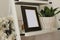 Blank wooden photo frame surrounded by home plants. Comfy details in the bedroom