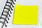 Blank yellow stick note on a spiral notebook from above. Removable self-stick notes.