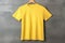 Blank yellow t-shirt on wooden hanger on grey background