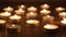 Blazing candles arranged in alignments on brown toned wooden table. Videography at night.
