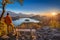 Bled, Slovenia - Traveller wearing orange jacket and hat enjoying the panoramic autumn sunrise view of Julian Alps