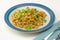 Blend of couscous, orzo, garbanzo beans, red quinoa cooked with shrimps and served with green peas and green onion close up