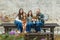 Blended family of five with two girls and a baby boy sitting on a table by an urban old brick wall