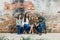 Blended family of five with two girls and a baby boy sitting on a table by an urban old brick wall