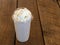 Blended Iced coffee frappe with whipped cream on a wood background.