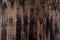 Blended vertical stripes of thick paint in shades of black and brown on wooden plank