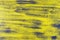 Blended vertical stripes of thick paint in shades of yellow and gray on wooden plank