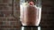 Blender with a banana strawberry milk smoothie on the kitchen, slow motion