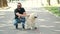 Blind bearded man with a cane and labrador sitting on pavement in park