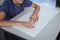 Blind caucasian schoolboy sitting at desk reading braille book with fingers