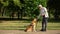 Blind man training guide dog in park, giving obedience commands and feeding