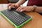 A blind man uses a computer with a Braille display and a computer keyboard. Inclusive device.