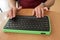 A blind man uses a computer with a Braille display and a computer keyboard. Inclusive device.