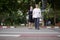 Blind person Asian woman with white cane crossing street walking on crosswalk with the sighted guide person senior woman by