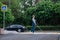 Blind pregnant woman crosses the road at a crosswalk with a cane.