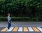 Blind pregnant woman crosses the road at a crosswalk with a cane.