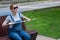 Blind pregnant woman folding walking stick while sitting on bench.