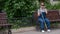 A blind pregnant woman sits on a bench and communicates on a smartphone.