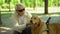 Blind senior man lovingly stroking guide dog, feeding pet in gratitude for help