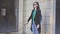 A blind woman wearing glasses with a cane walking in front of shop windows