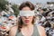 Blindfolded female volunteer in a landfill of plastic trash.