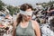 Blindfolded female volunteer in a landfill of plastic trash.