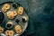 Blinis with black caviar and cream cheese, overhead flat lay shot on black