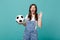 Blinking woman football fan cheer up support favorite team with soccer ball showing OK gesture isolated on blue