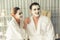 Blissful couple in bathrobe with facial cream mask. Quiescent
