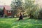 Blissful fat woman doing exercises for stretching legs green grass on backyard of cottage with wooden house and trees in