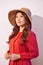 Blissful lady with broad smile posing in sunny day. Laughing girl in red clothes and trendy straw hat enjoying good weather in