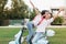 Blissful male model posing with peace sign while girl with black hair kissing him on nature background. Trendy young