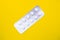 A blister pack of statins, pills tablets for lowering cholesterol on yellow background, prevention and treatment of
