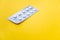 A blister pack of statins, pills tablets for lowering cholesterol on yellow background, prevention and treatment of