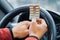 Blister of pills in the hands of the driver on a blurred background of the steering wheel in the car