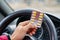 Blister of pills in the hands of the driver on a blurred background of the steering wheel in the car