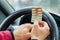 Blister of pills in the hands of the driver on a blurred background of the steering wheel in the car