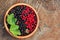 Bllack and red currant and green leaves in wooden bowl.