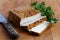 Block of smoked tofu, two tofu slices, rustic knife and fresh p