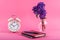 Blog concept image with old clock, notebooks and flowers in a vase on a pink background