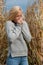 Blog style fashion photo of cute blond woman on corn field in late autumn